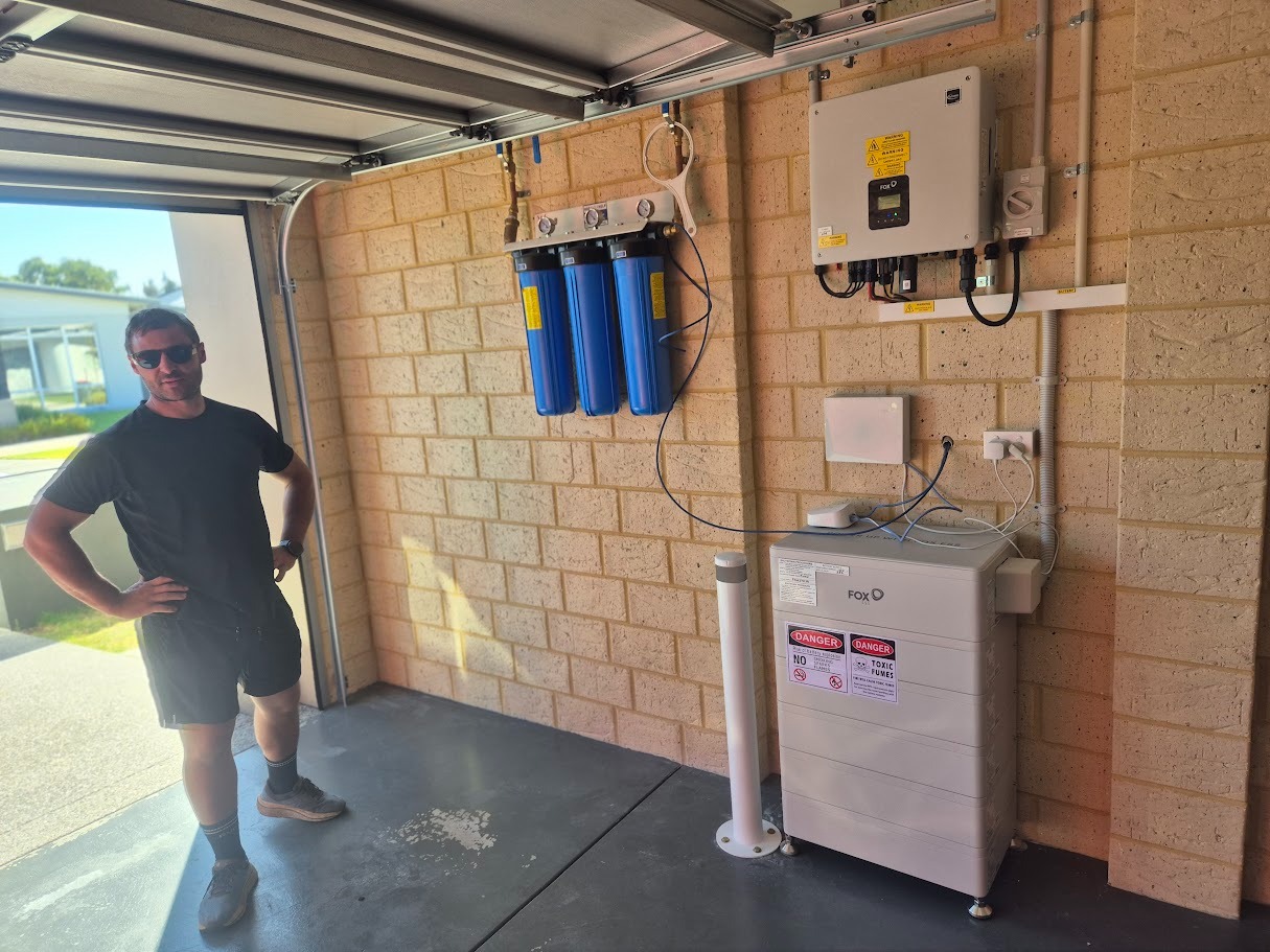 Person standing beside a completed FoxESS battery and inverter installation